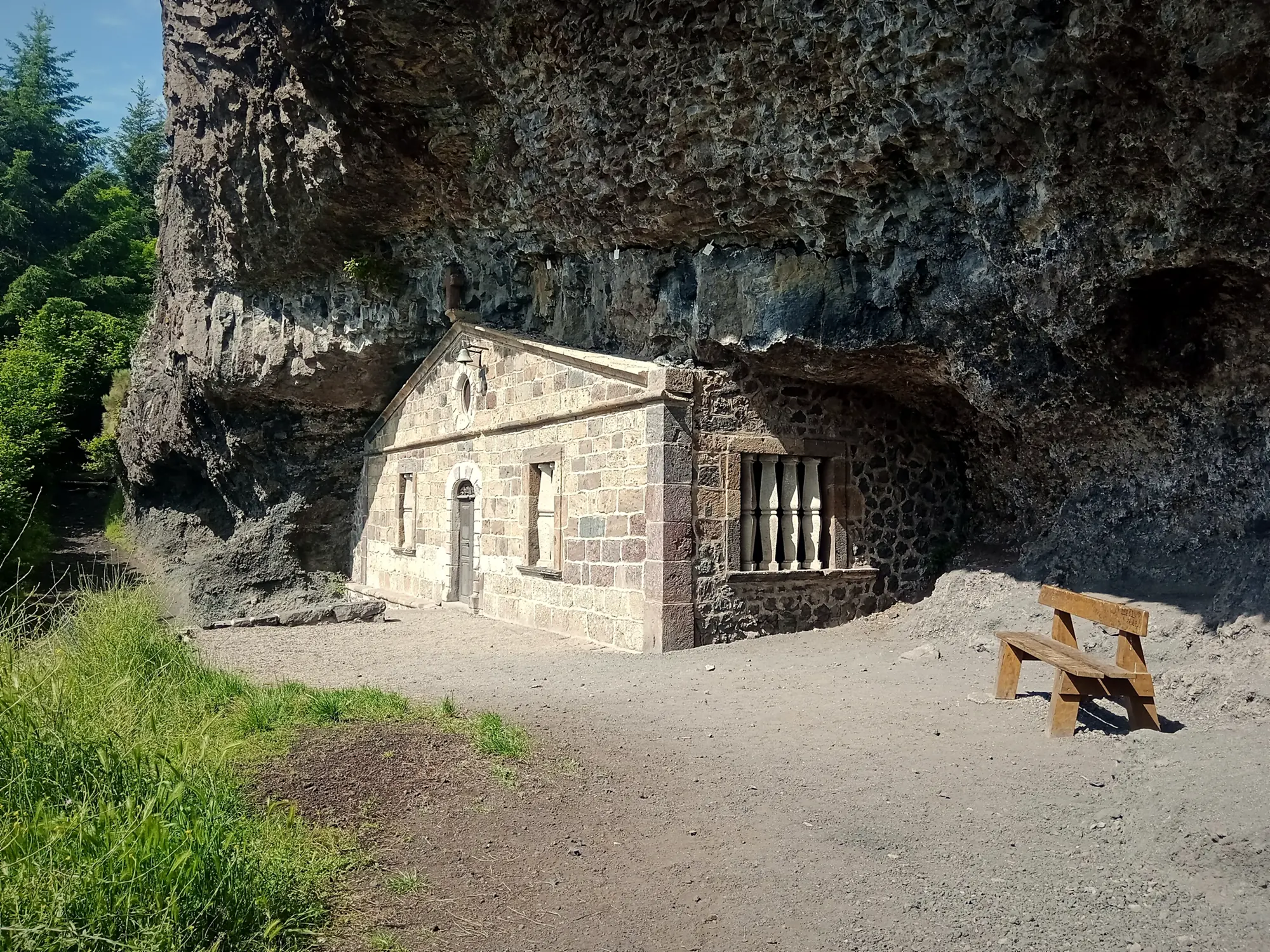The stone facade of the Sainte-Madeleine chapel closing a cave in the volcanic rock